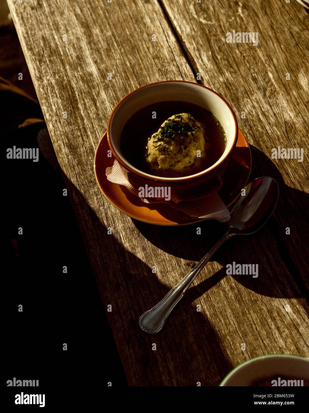 A closeup on a bowl of knödel suppe on a wooden table in Kitzbühel, Austria. Stock Photo