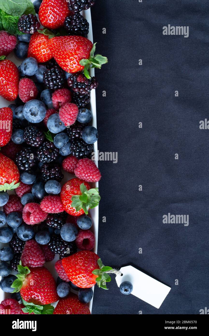 Strawberries, blackberries, rasberries, green mint on canvas black bakground. Mock up, menu, cafe poster concept Stock Photo