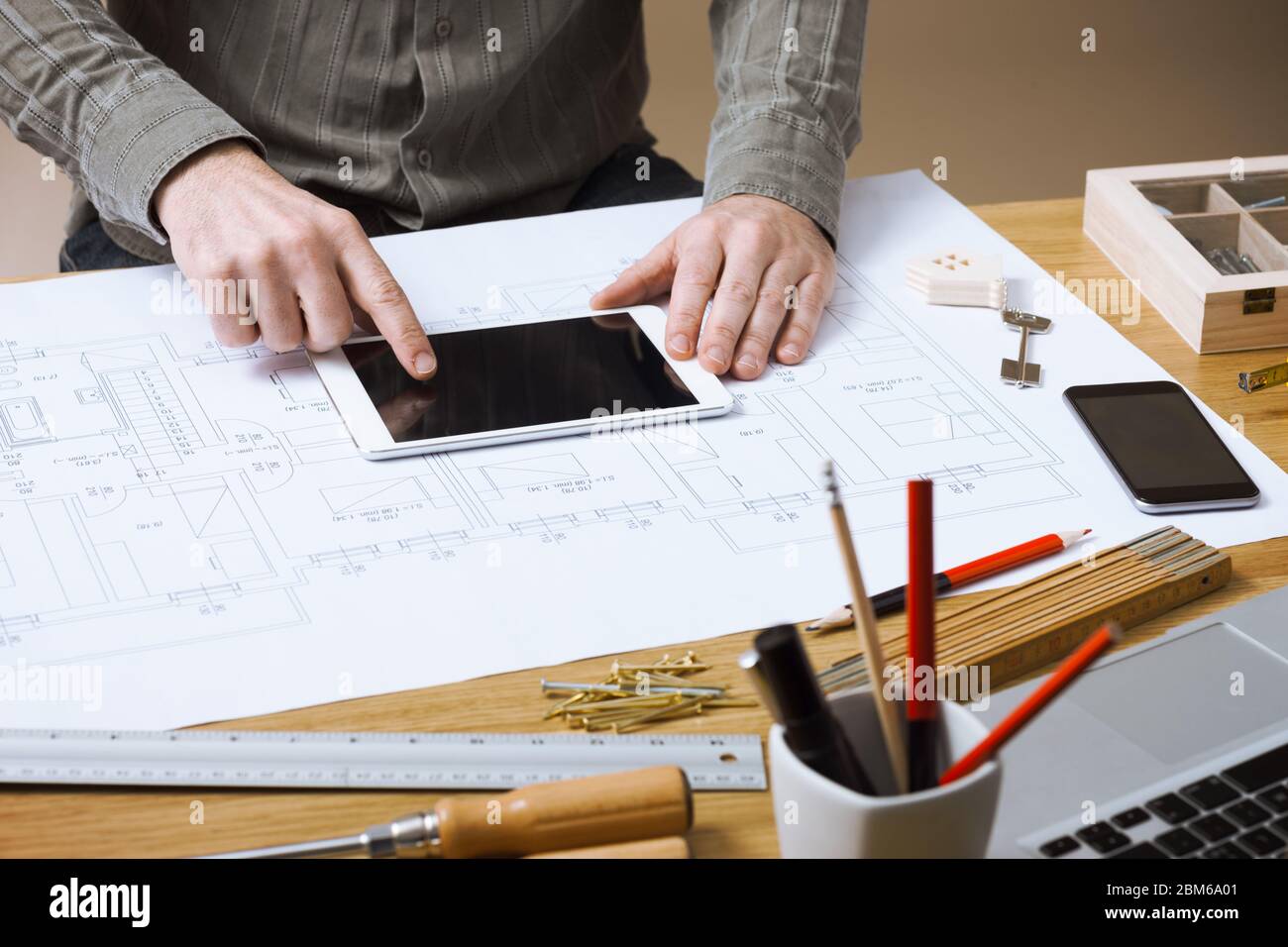 Professional architect and construction engineer working at office desk hands close-up, he is using a touch screen tablet Stock Photo