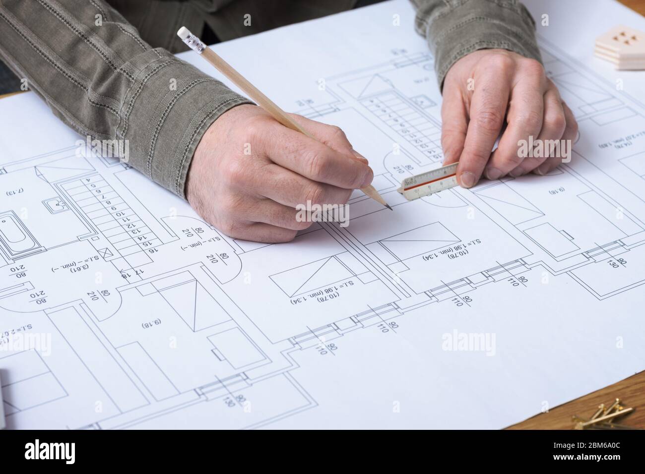 Professional architect and construction engineer working at office desk hands close-up, he is drawing on a building project with a pencil and a ruler Stock Photo