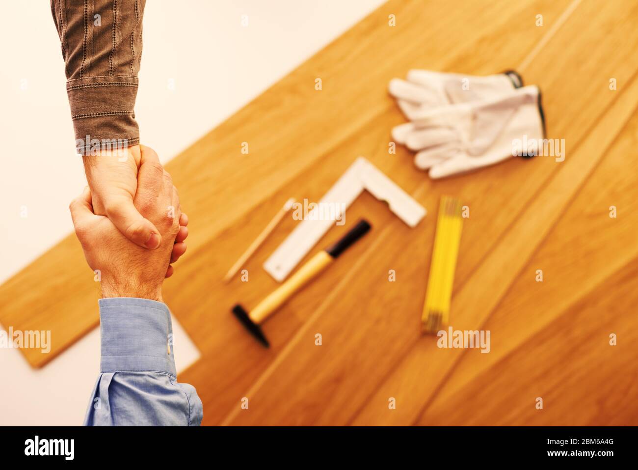 Contractor and customer shaking hands, wooden flooring installation and