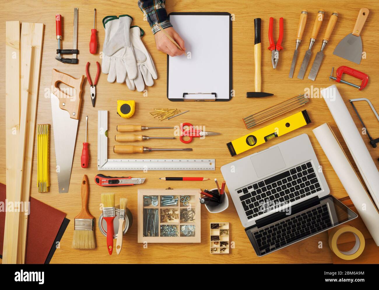Male hand sketching on a white clipboard top view, DIY work tools all around, carpentry and hobby concept Stock Photo
