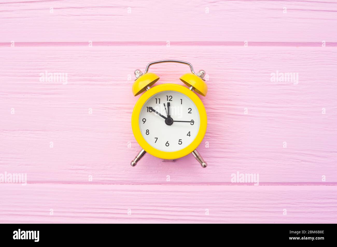 yellow old style alarm clock on pink wooden background with place for your text. Copyspace time concept Stock Photo