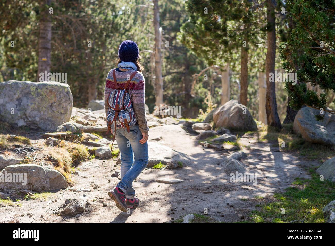 Back view of a backpacker woman wearing a wool cap hiking Stock Photo ...