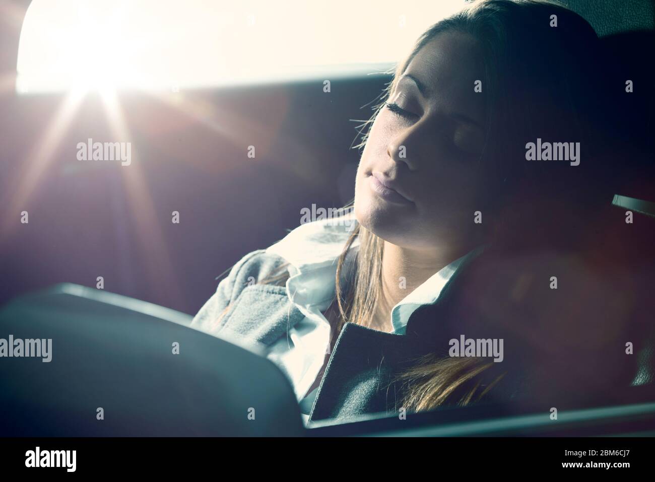 Exhausted young woman sleeping in a car with eyes closed. Stock Photo