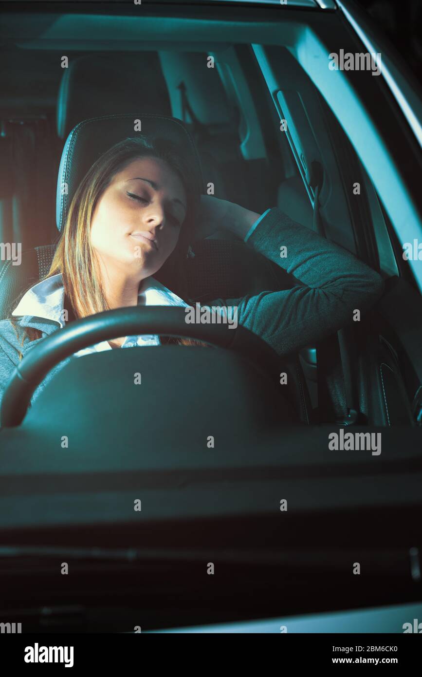 Exhausted young woman sleeping in a car with eyes closed. Stock Photo