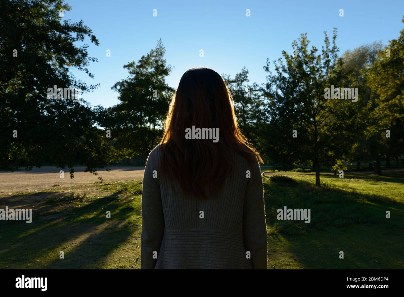 Rear view of young Asian woman looking towards grassy plain with nature Stock Photo