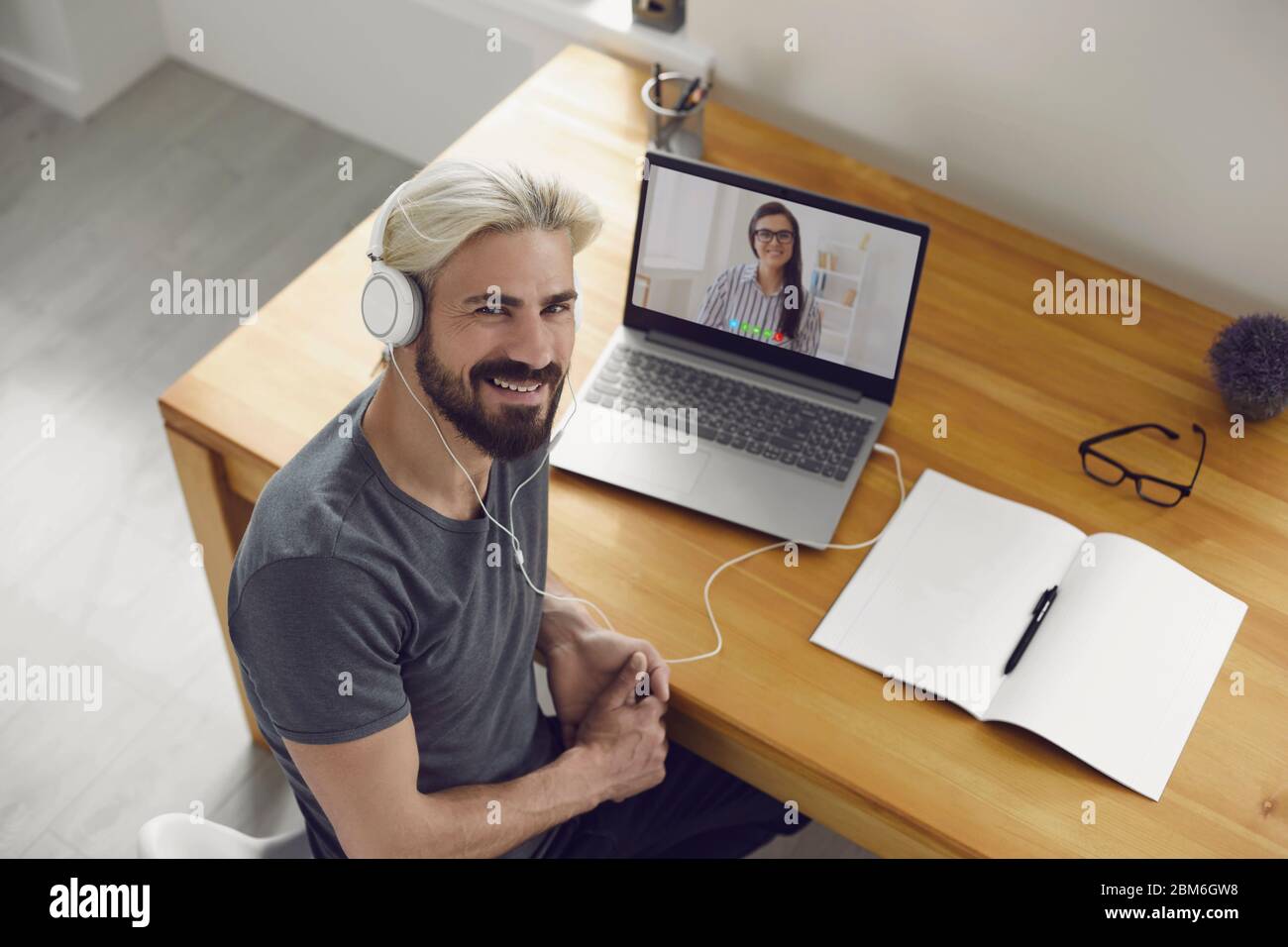 Education learning study online video call chat. Male student smiling is studying an online lesson with a teacher using a laptop webcam at home. Stock Photo