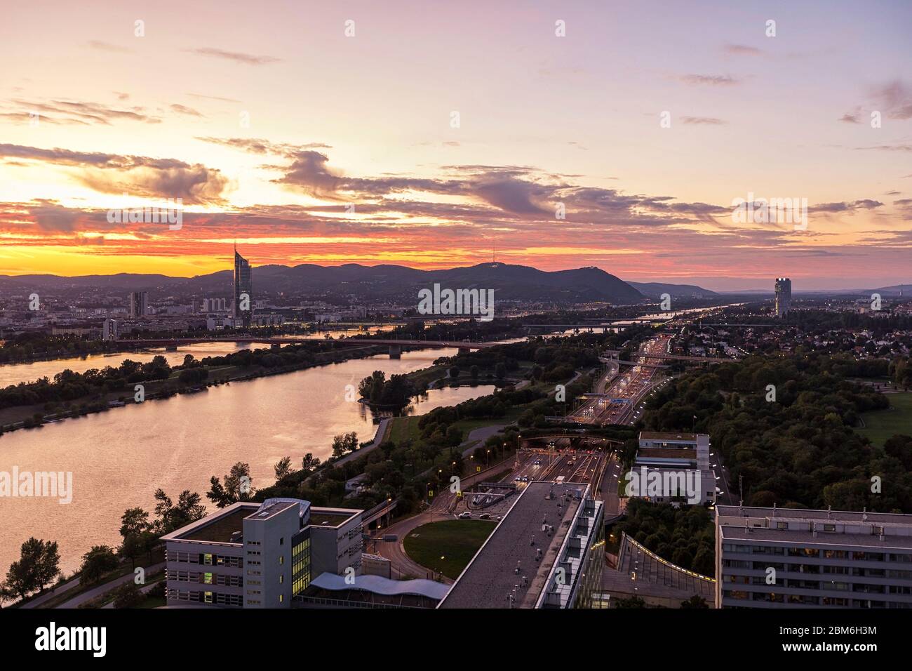 Dusk at the New Danube River with highway no. A22, the public recreation area called Danube Island, the Vienna Woods and Kahlenberg in the background Stock Photo