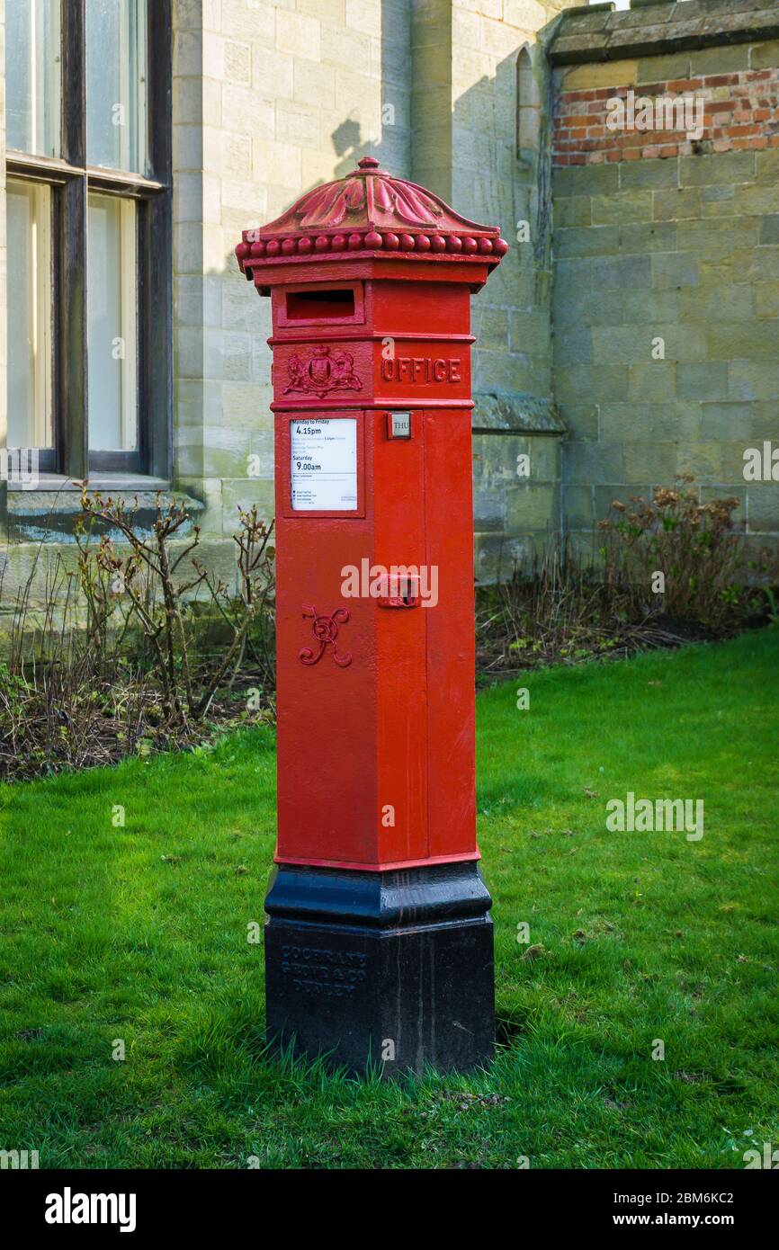 Traditional British red post box designed by John Penfold in the grounds of Chiddingstone Castle in Kent, UK Stock Photo