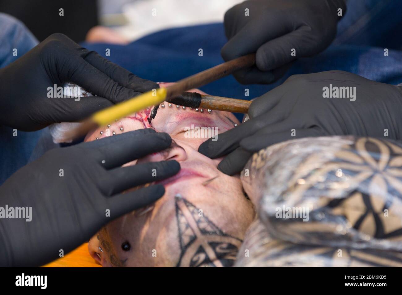 Man having his face tattooed by the Polynesian Method. This method involves a comb of needles being tapped in to the skin with stick by hand. The Lond Stock Photo