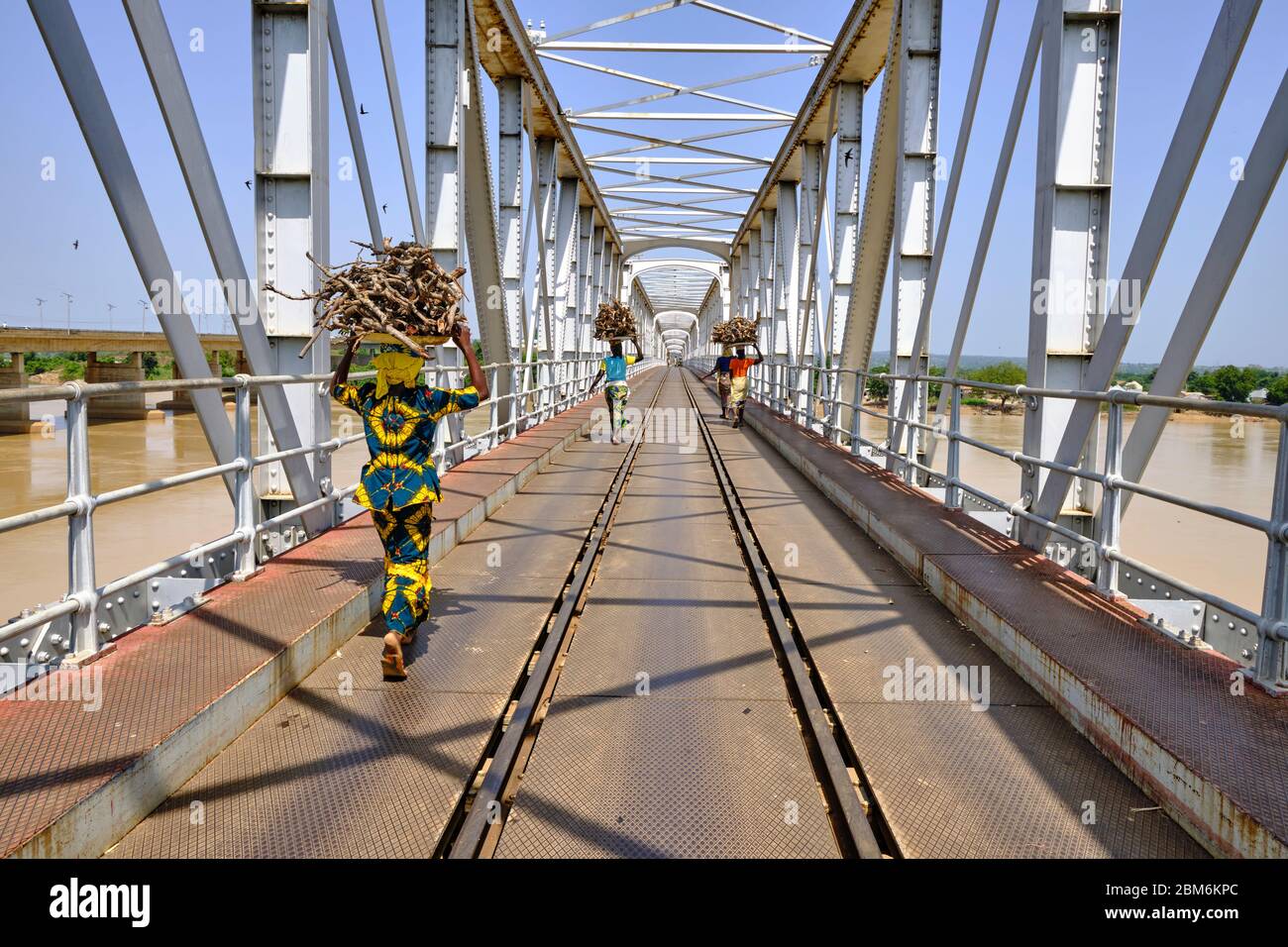 Women with a load on their head crossing river Niger using the railway bridge at Jebba. Stock Photo