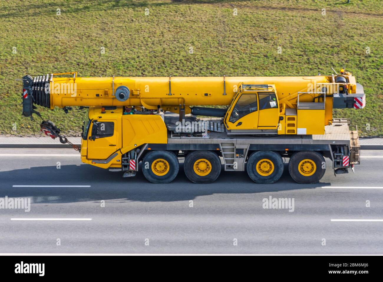 Heavy mobile crane with folding boom construction rides on a city