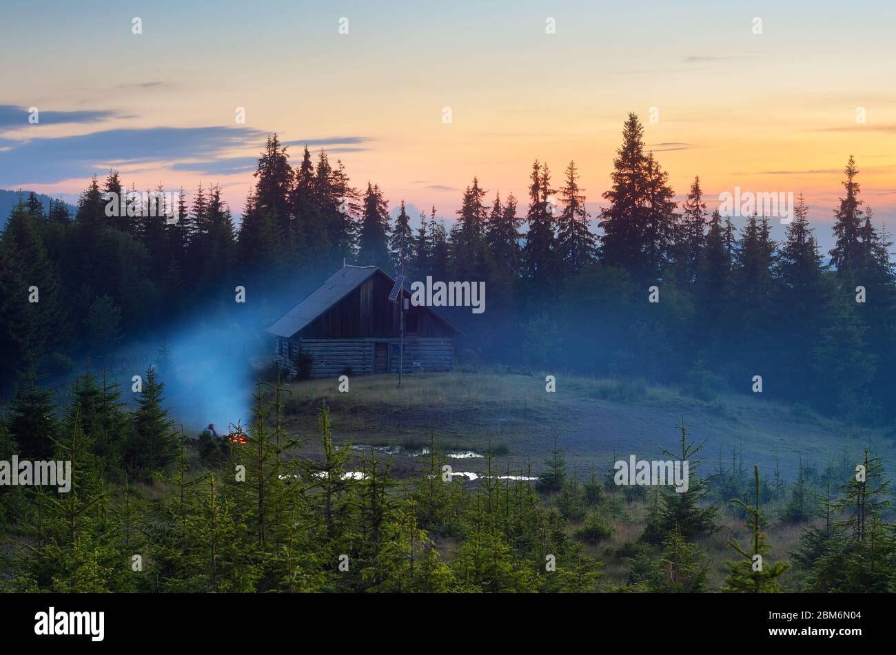 Summer evening. Mountain landscape. Camping in nature. Bonfire near the house Stock Photo