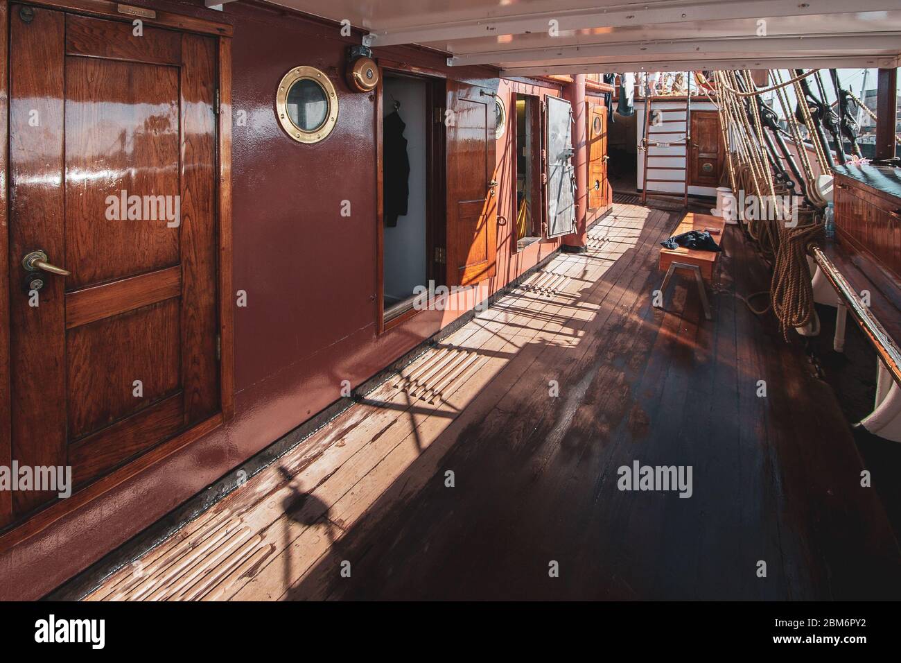 Deck of a retro sailboat with cabin entrances. Red shiny lacquered