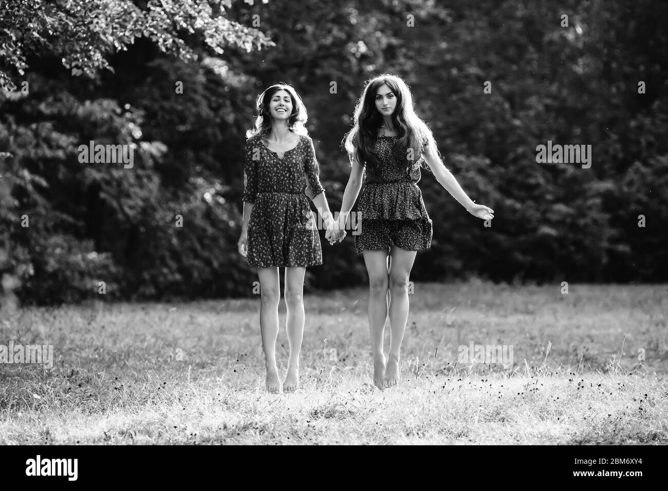 Two young smiling women levitate in the park black and white colors Stock Photo