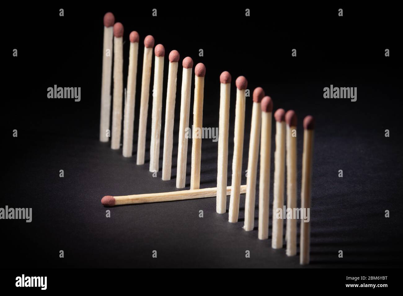 A row of upright unburnt matchsticks with one lying down out of the line Stock Photo