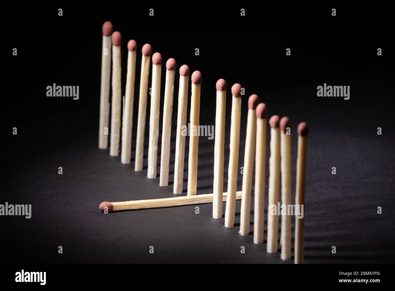 A row of upright unburnt matchsticks with one lying down out of the line Stock Photo