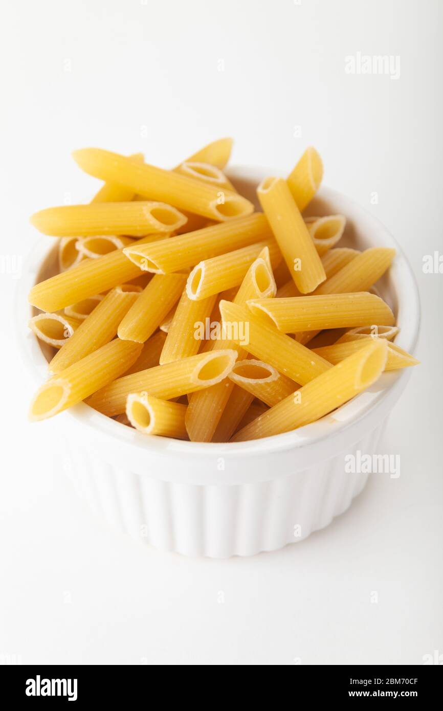 Penne pasta photographed in a ramekin dish on a white background Stock Photo