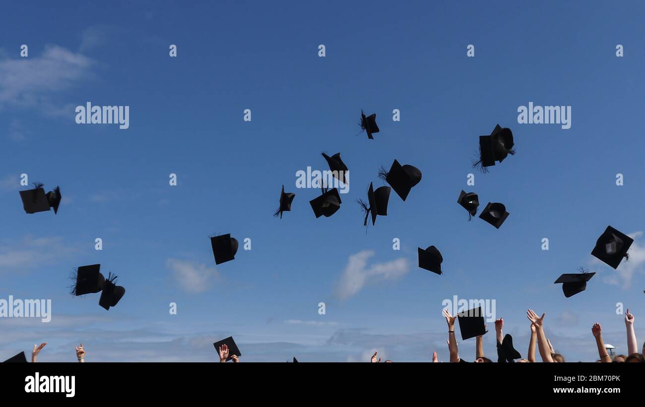 Graduates celebrating throwing caps in the air Stock Photo