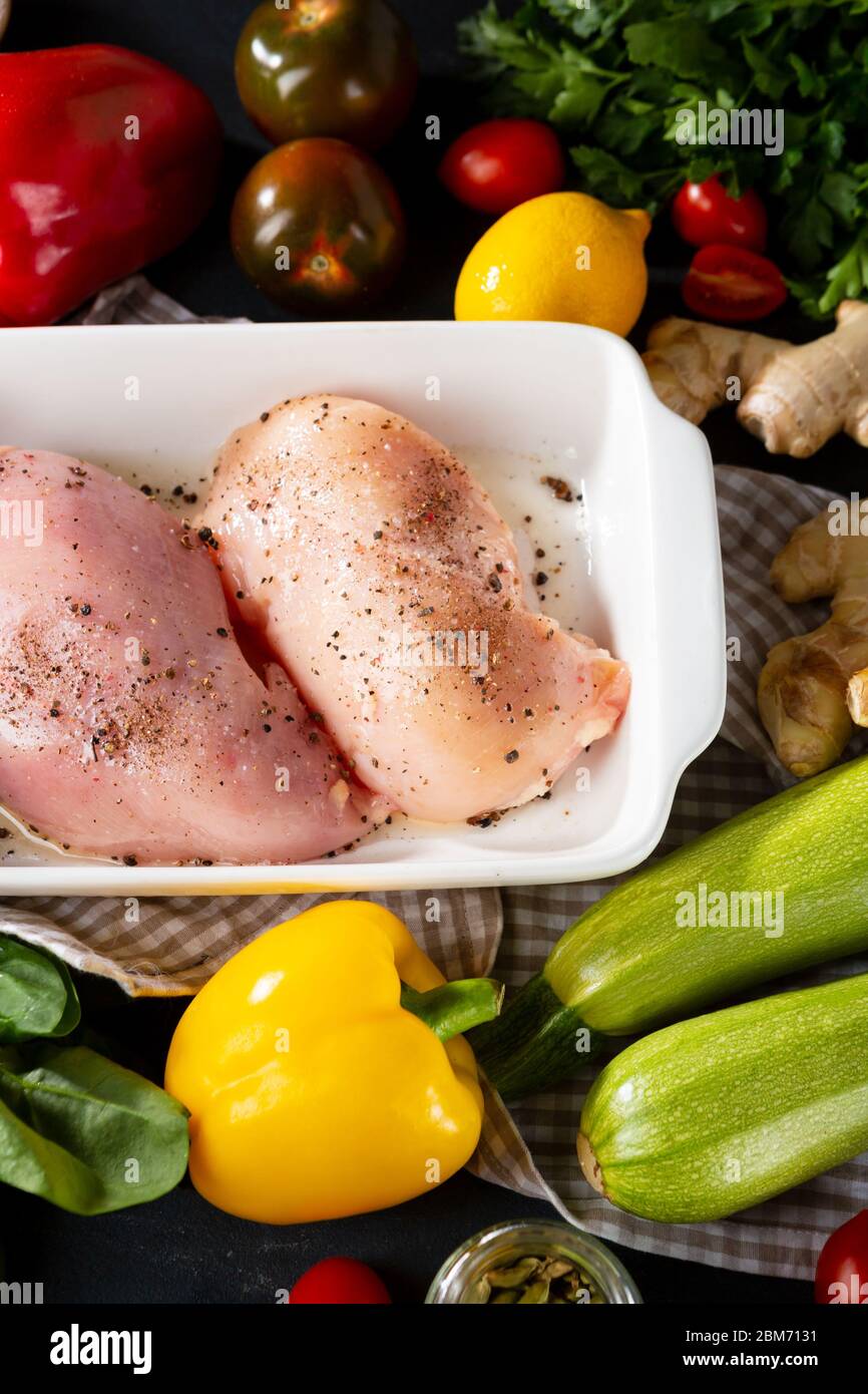 Chicken in baking dish and fresh veggies ready for roat Stock Photo