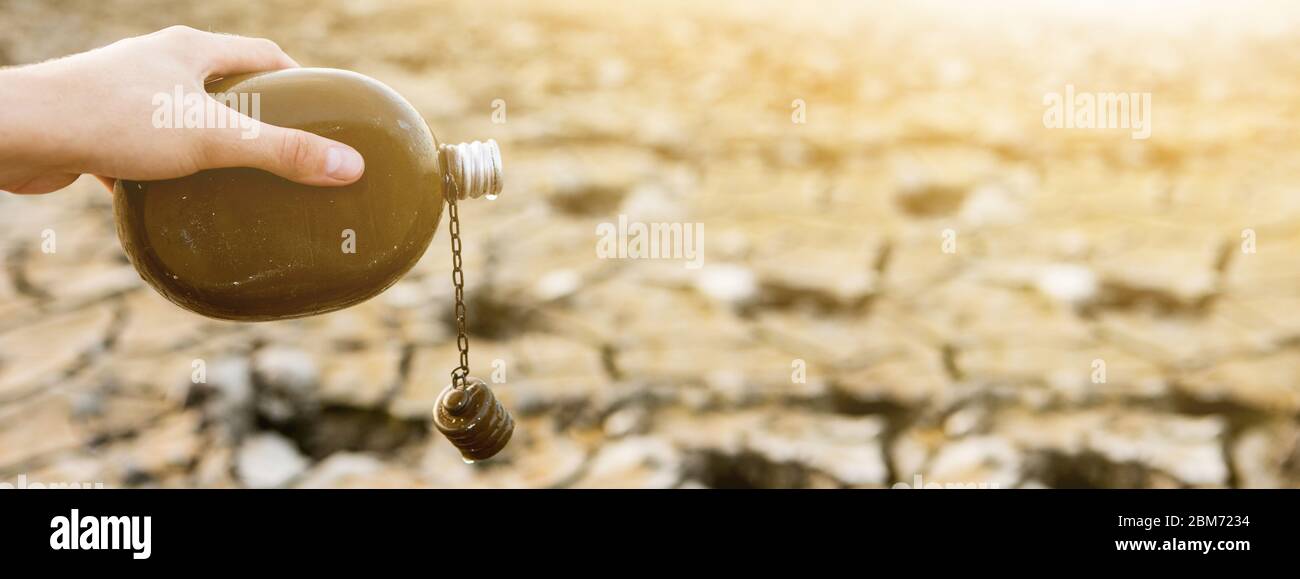 Man with flask in the desert. Drought and water scarcity caused by global warming Stock Photo