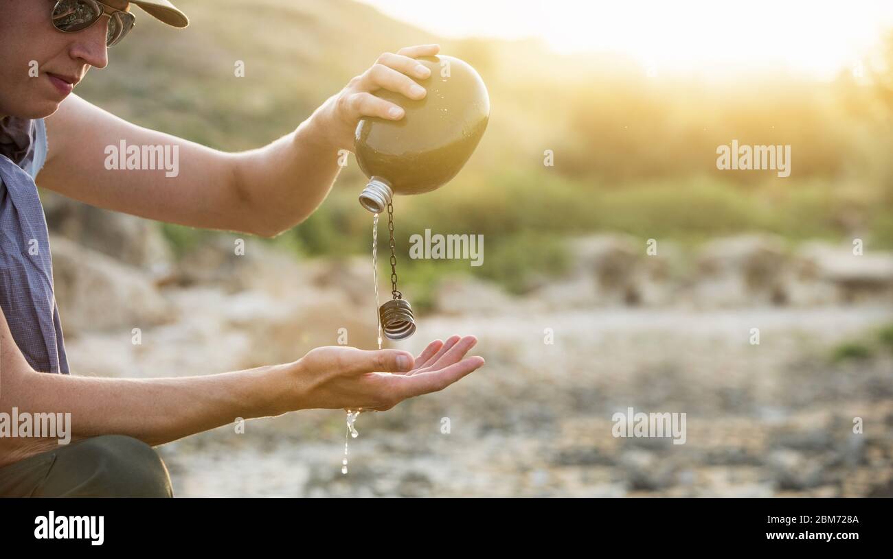 Man with flask in the desert. Drought and water scarcity caused by global warming Stock Photo