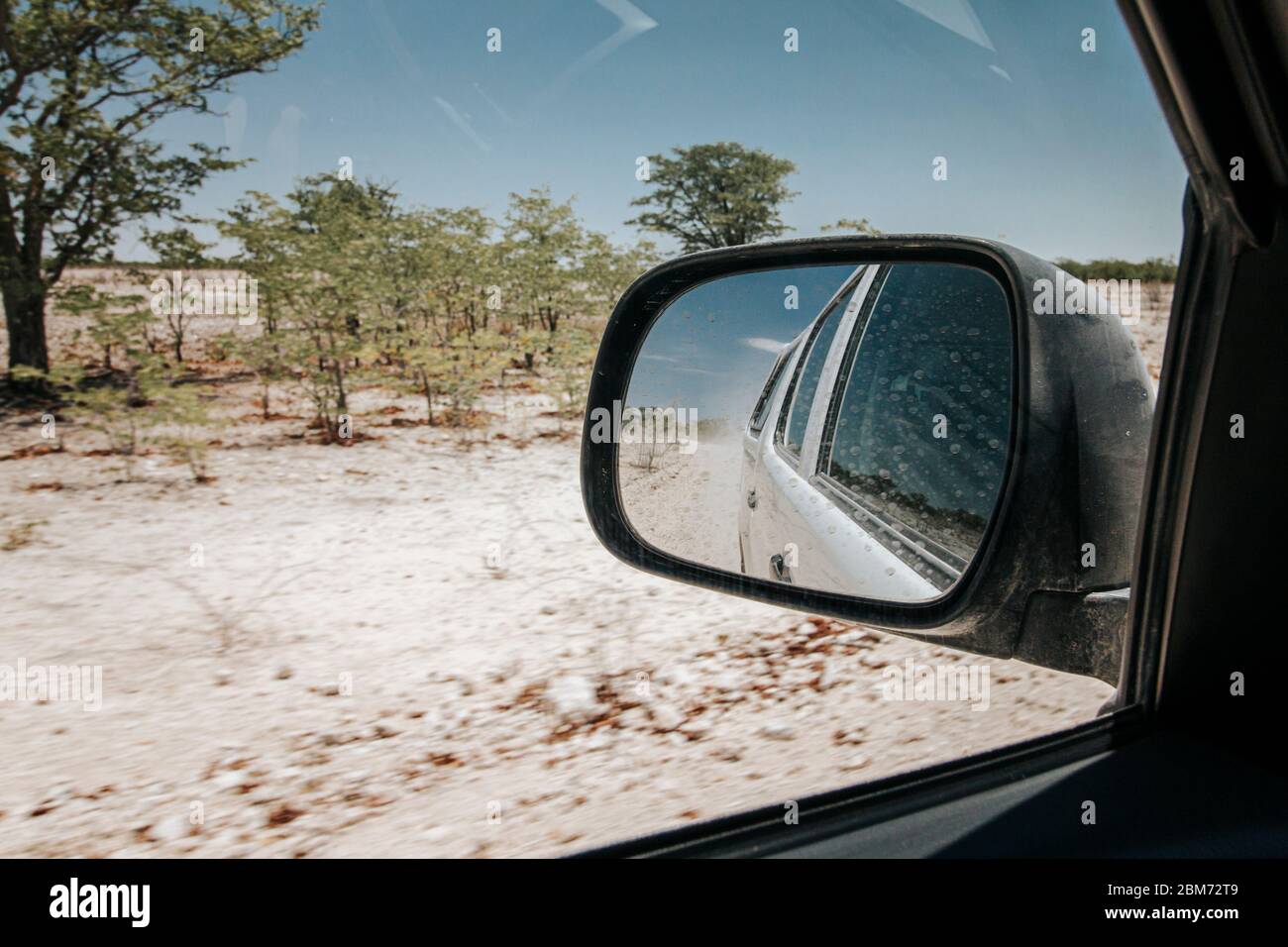 View in rear view mirror while driving through arid dry landscape in Etosha national park Namibia. Stock Photo