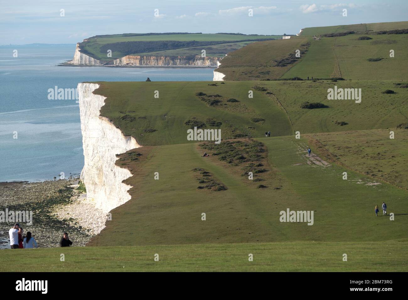 Walkers on the undulating Seven Sisters cliff path, part of the South Downs Way in East Sussex Stock Photo