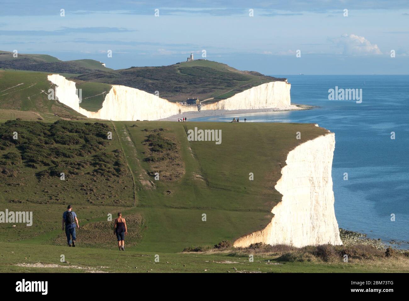 Walkers on the Seven Sisters cliff path, part of the South Downs Way in East Sussex (also shows Birling Gap and the Belle Tout Lighthouse) Stock Photo