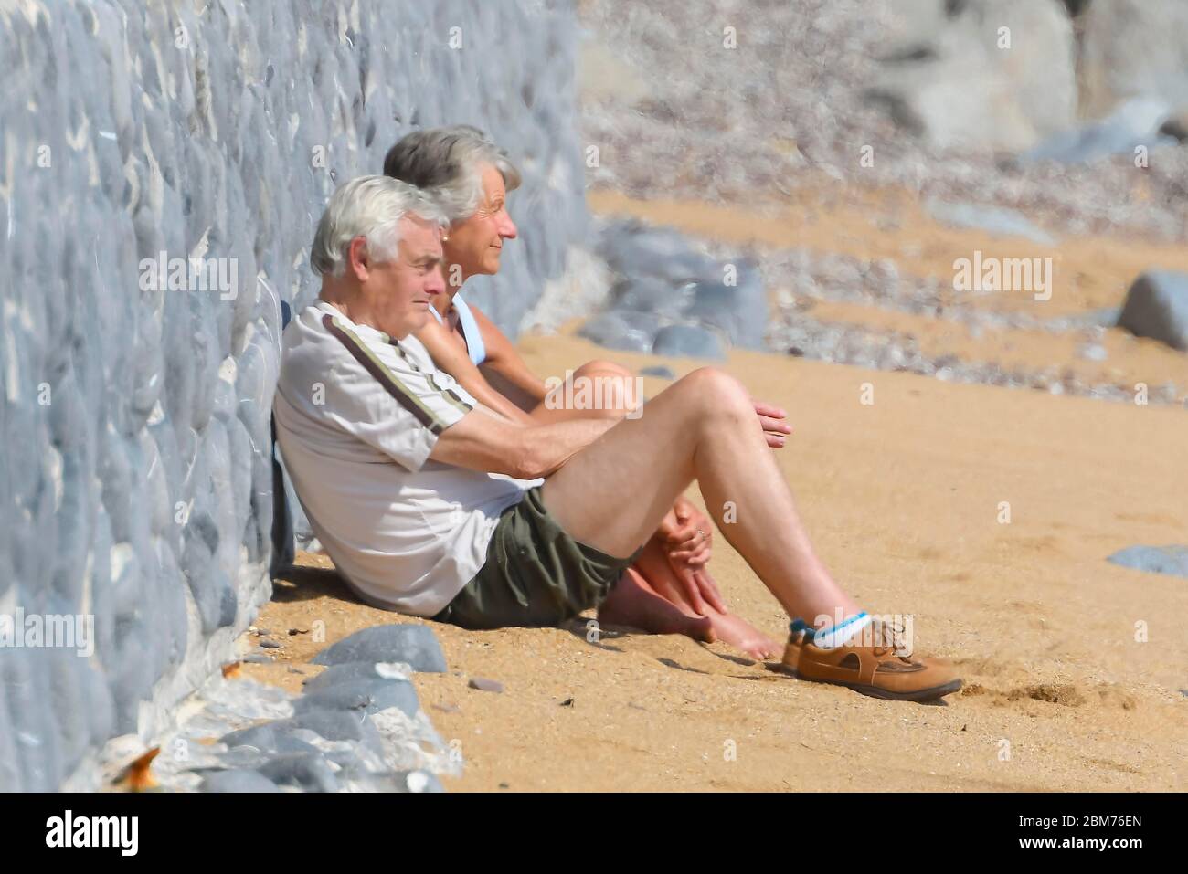 West Bay, Dorset, UK.  7th May 2020. UK Weather.  A couple sitting on the beach at the seaside resort of West Bay in Dorset enjoying the hot sunshine during the coronavirus pandemic lockdown.   Picture Credit: Graham Hunt/Alamy Live News Stock Photo
