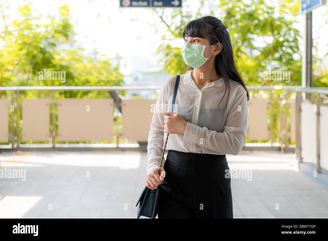 Young stress Asian businesswoman in white shirt going to work in pollution city she wears protection mask prevent PM2.5 dust, smog, air pollution and Stock Photo