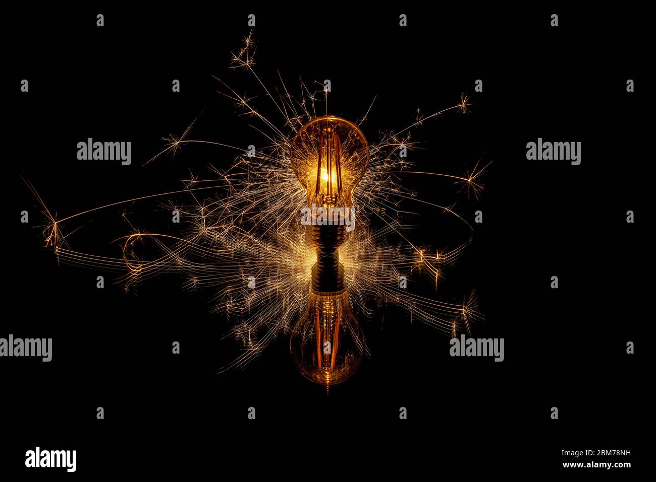 Glowing sparkler behind a retro light bulb Stock Photo