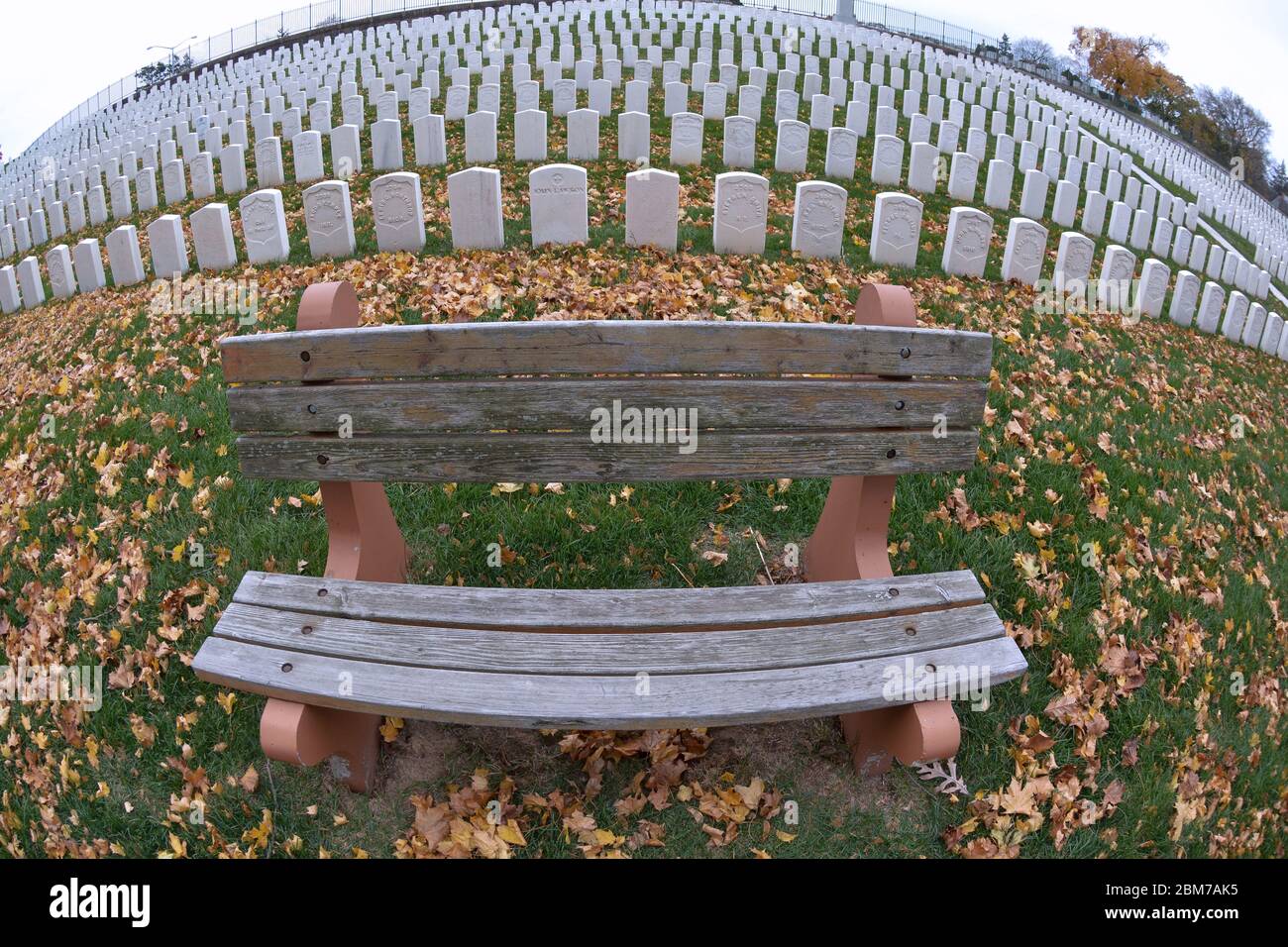 A fisheye view of n empty bench on a fall day at Cyprus Hills National Cemetery in Brooklyn, New York. Stock Photo