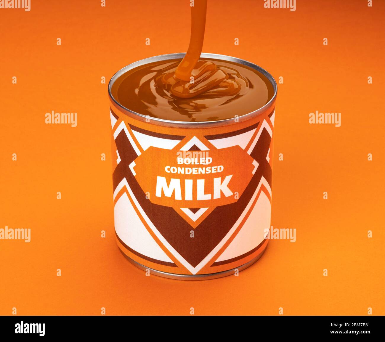 Flowing boiled condensed milk into can on orange background Stock Photo