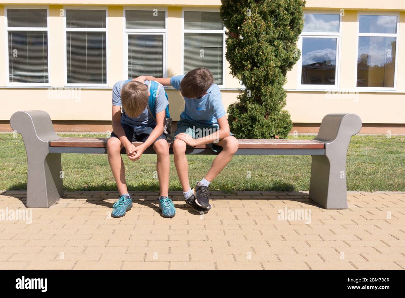 Kid comforting consoling upset sad friend in school yard. Problems at school, learning difficulties. Stock Photo