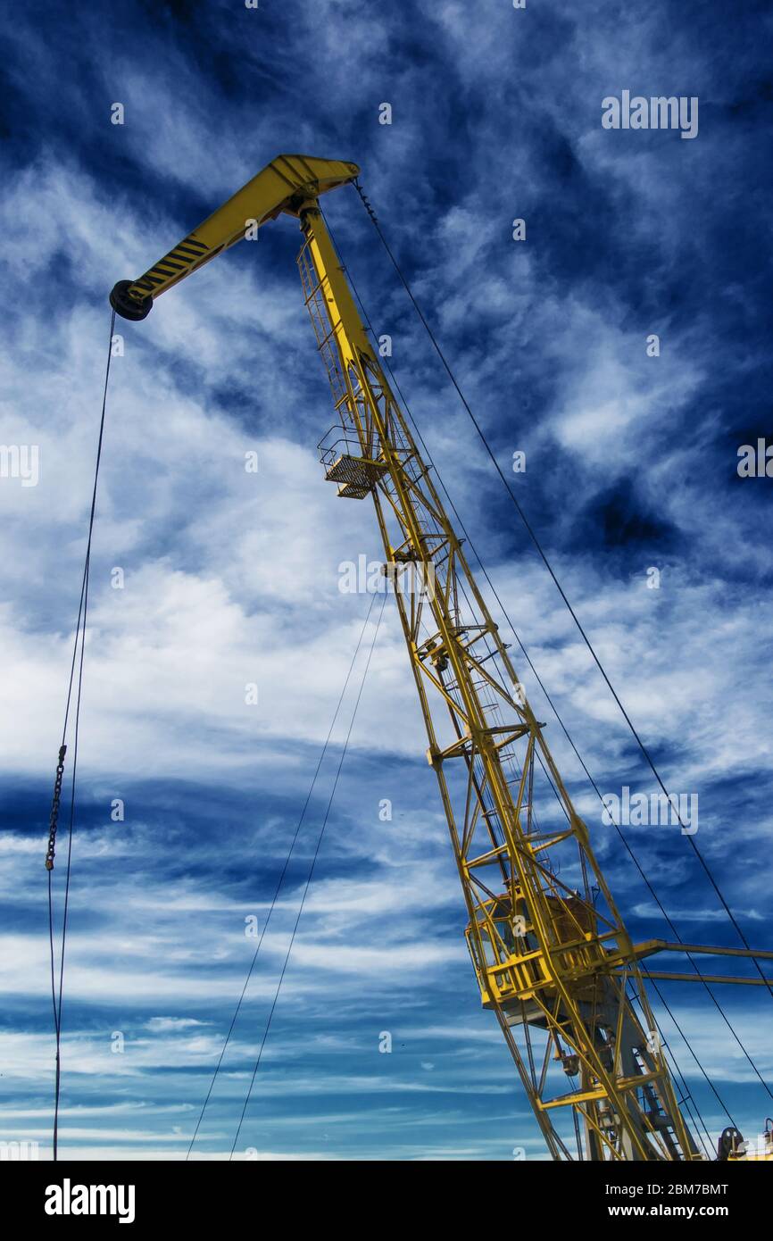 the little crane mounted on a river boat on the background of blue sky with clouds Stock Photo