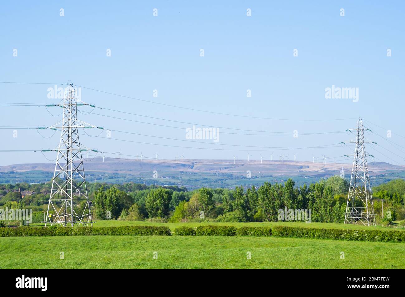 Electricity pylons in England with wind farm in background English pylons fields field