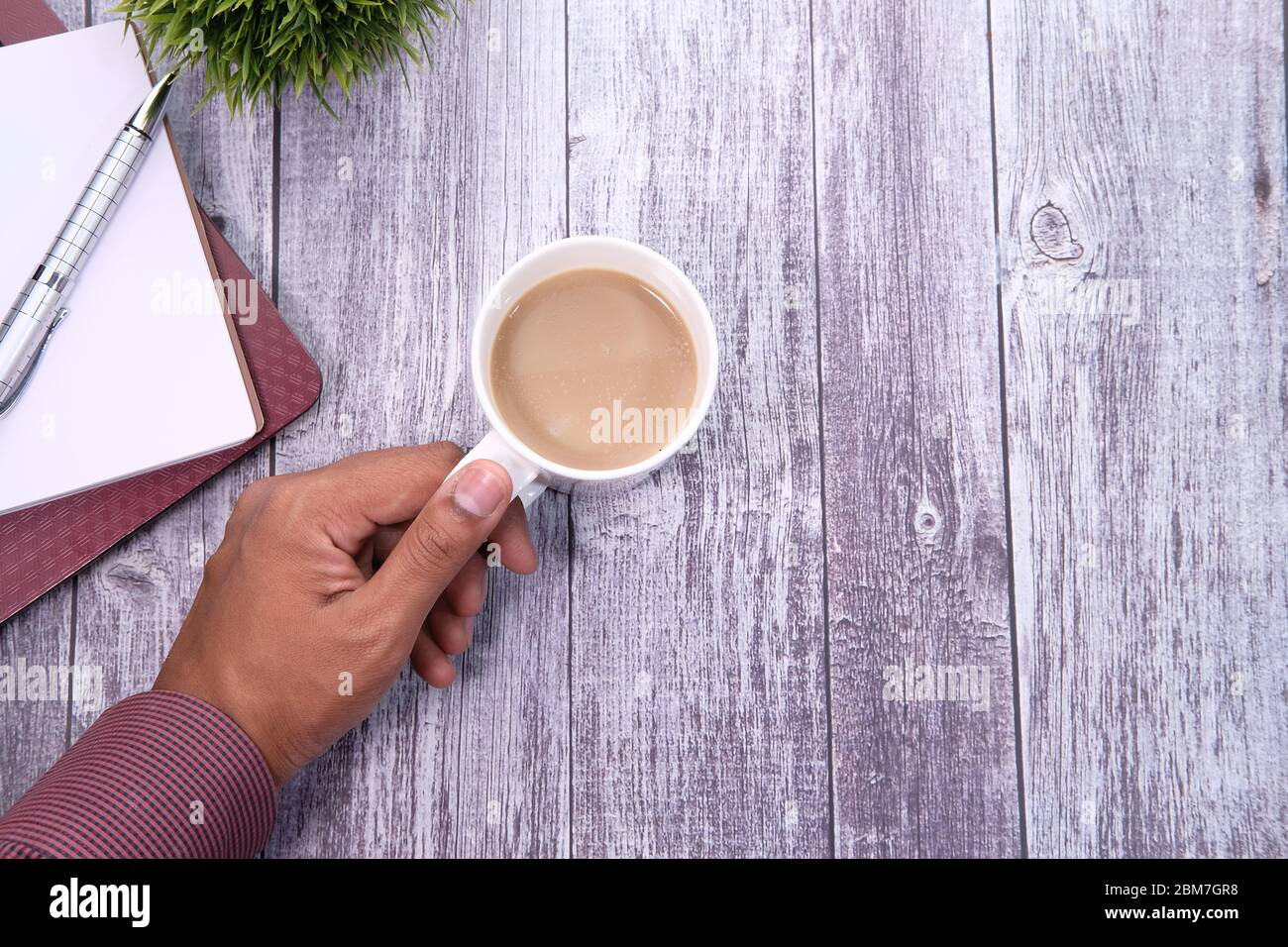 young man hand holding tea cup on table, top view. Stock Photo