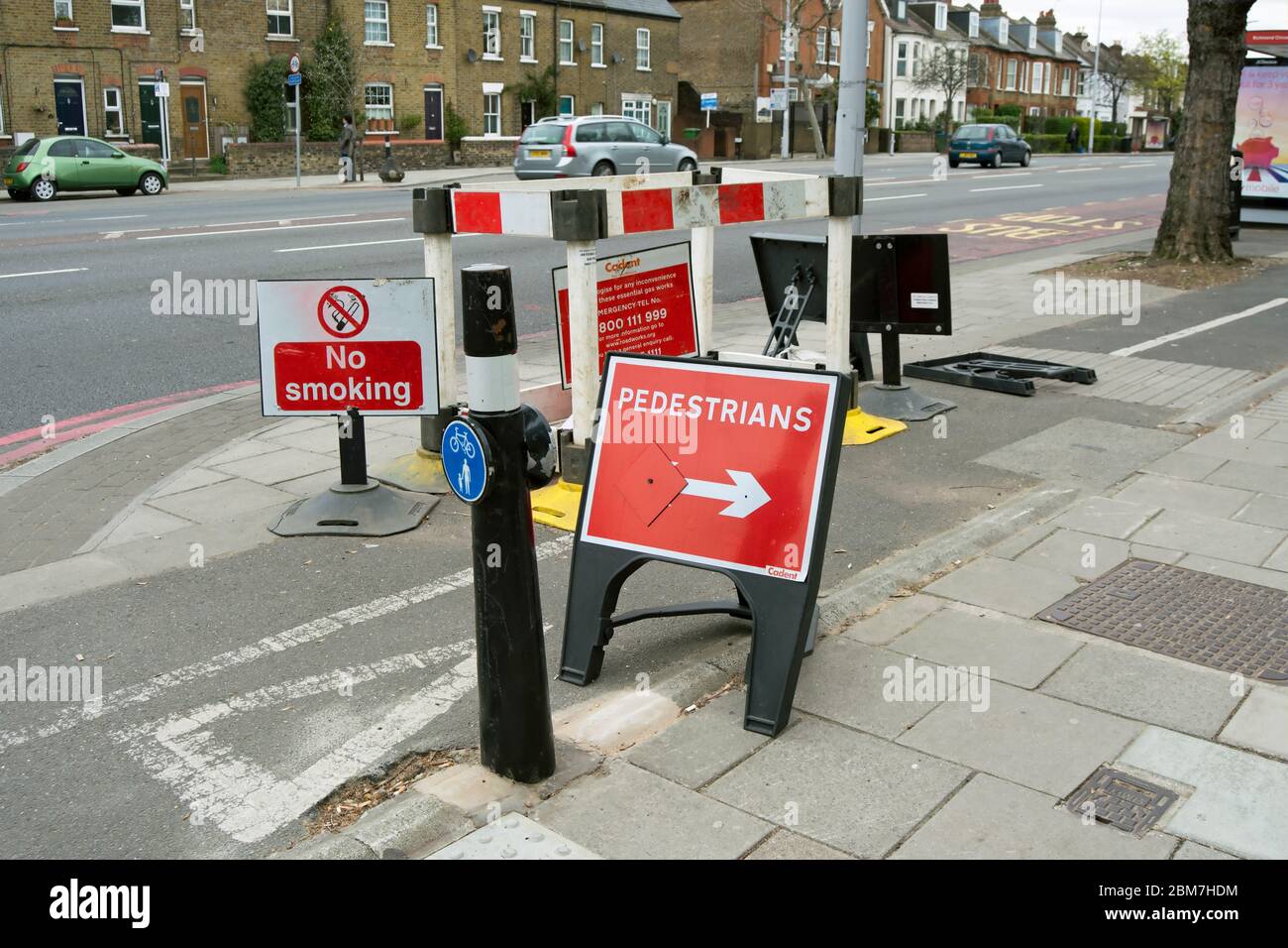 a clutter of signs at a gas pipe repair on a cycle track in richmond, surrey, england, including a needless sign directing pedestrians to the footway Stock Photo