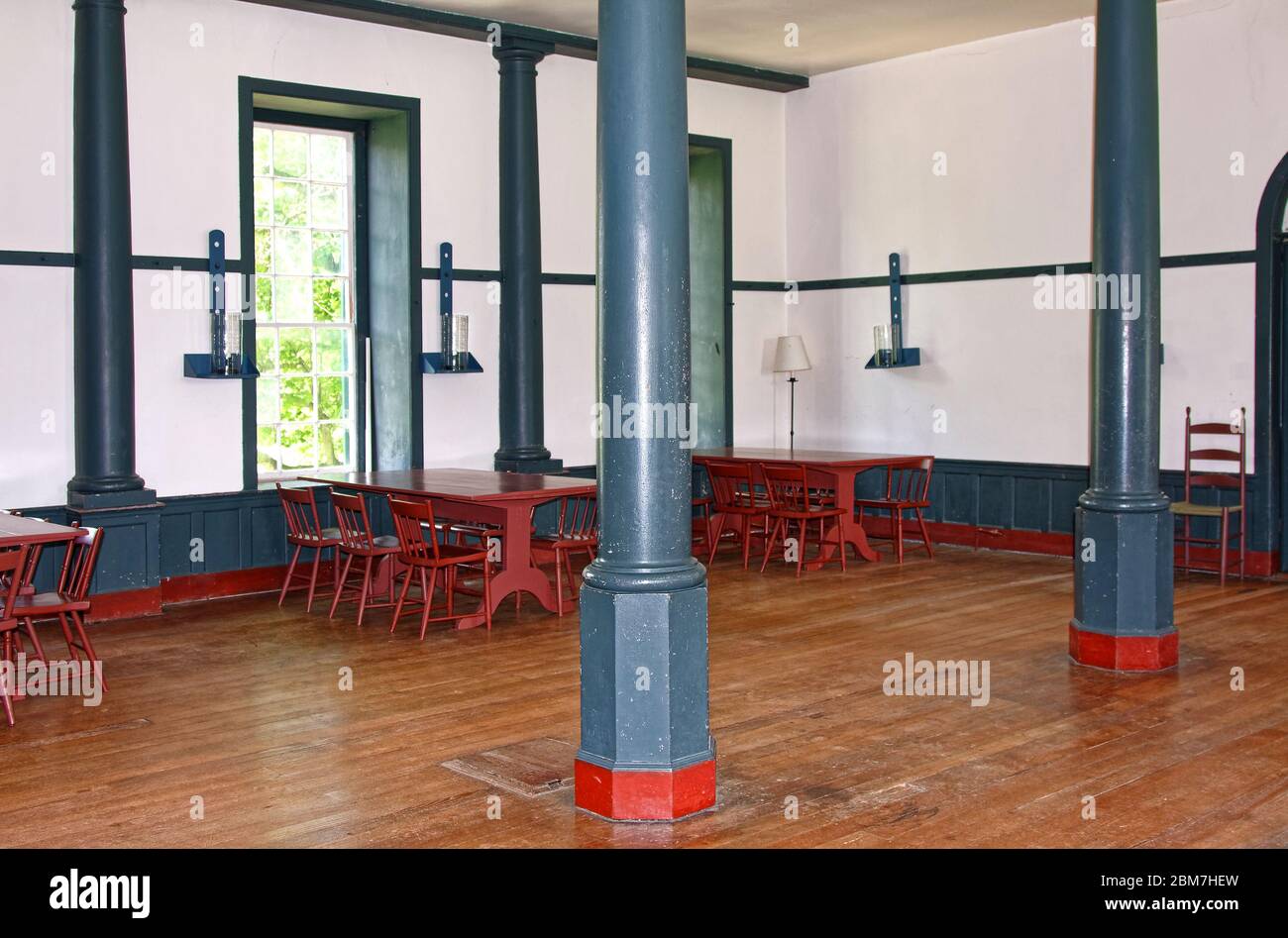 original dining room, plain tables, chairs, pillars, wood floor, hanging candles, unadorned walls, Shaker Village of Pleasant Hill, defunct religious Stock Photo