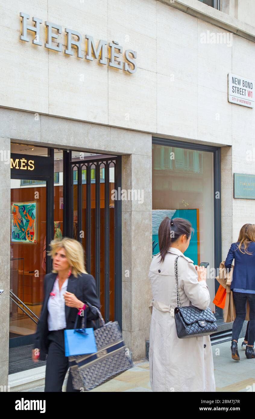 Smart-looking international shoppers walking past the Hermes luxury brand store on Bond Street in the West End of London, UK Stock Photo