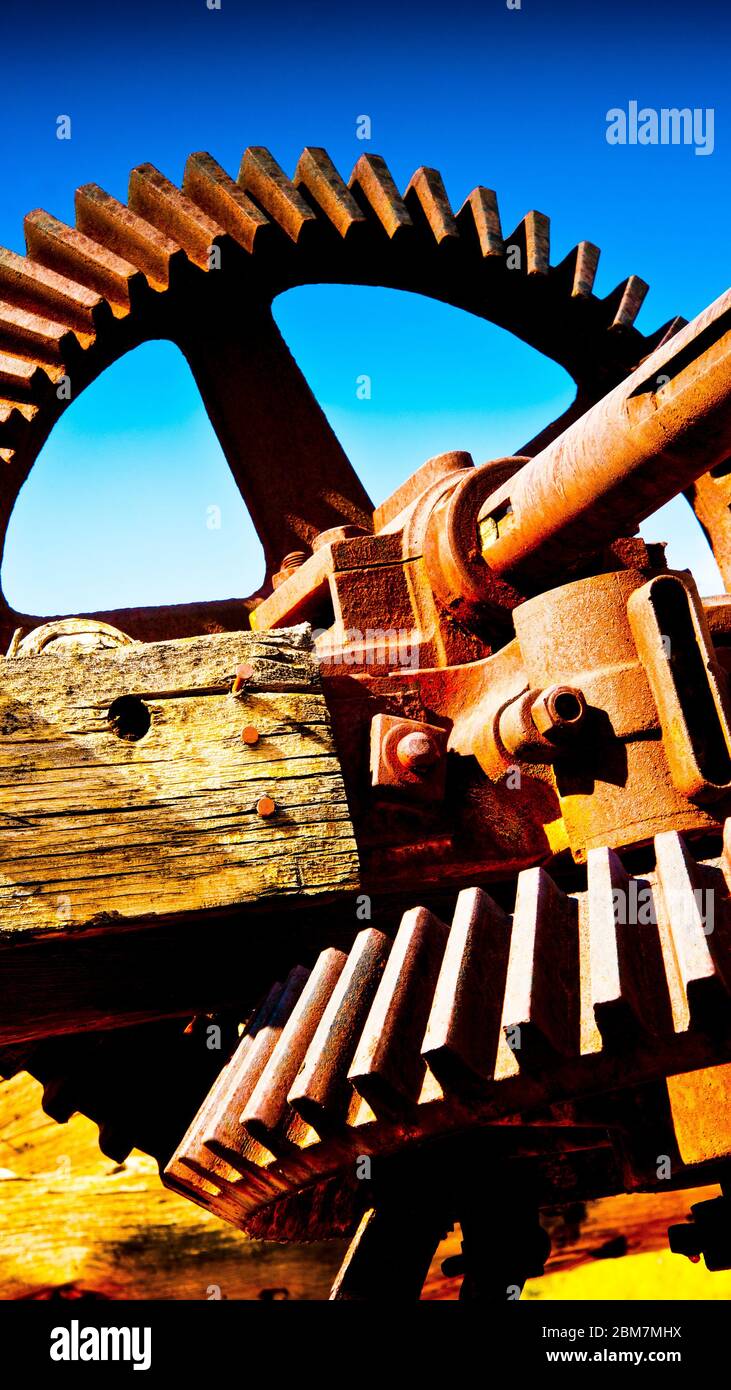 artistic view from a bygone aged of heavy mechanical engineering,rusting old gear wheel and driveshaft, disused mining parts. Stock Photo