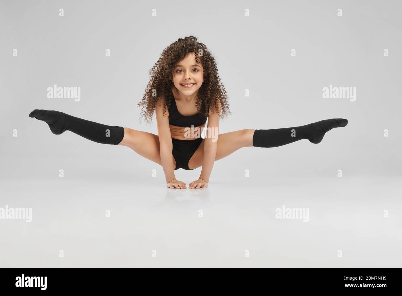 Little girl doing gymnastics with hoop, ball and split isolated on grey  background, studio Stock Photo - Alamy