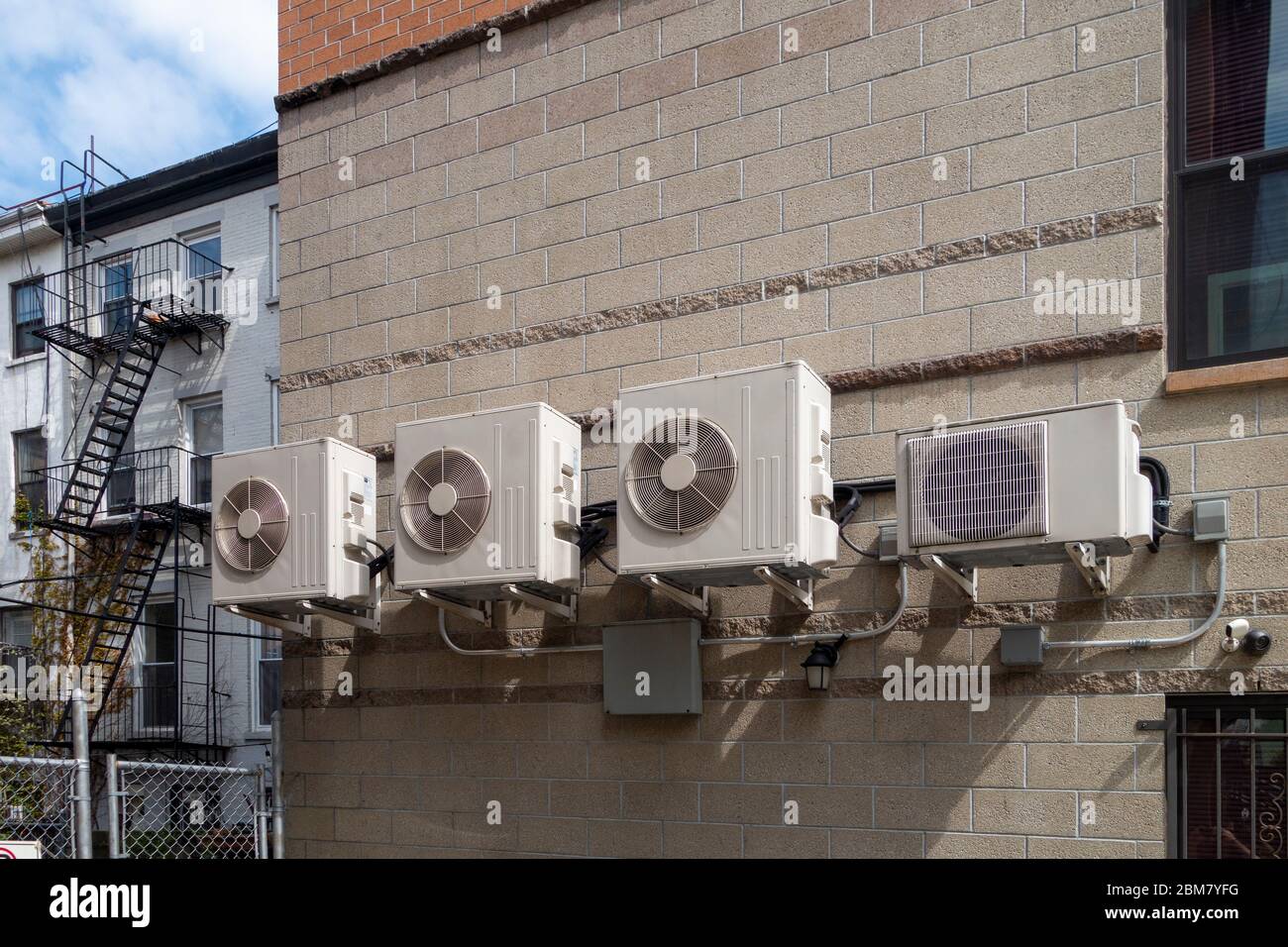 tan residential building exterior wall with several attached AC (air conditioning) unites Stock Photo