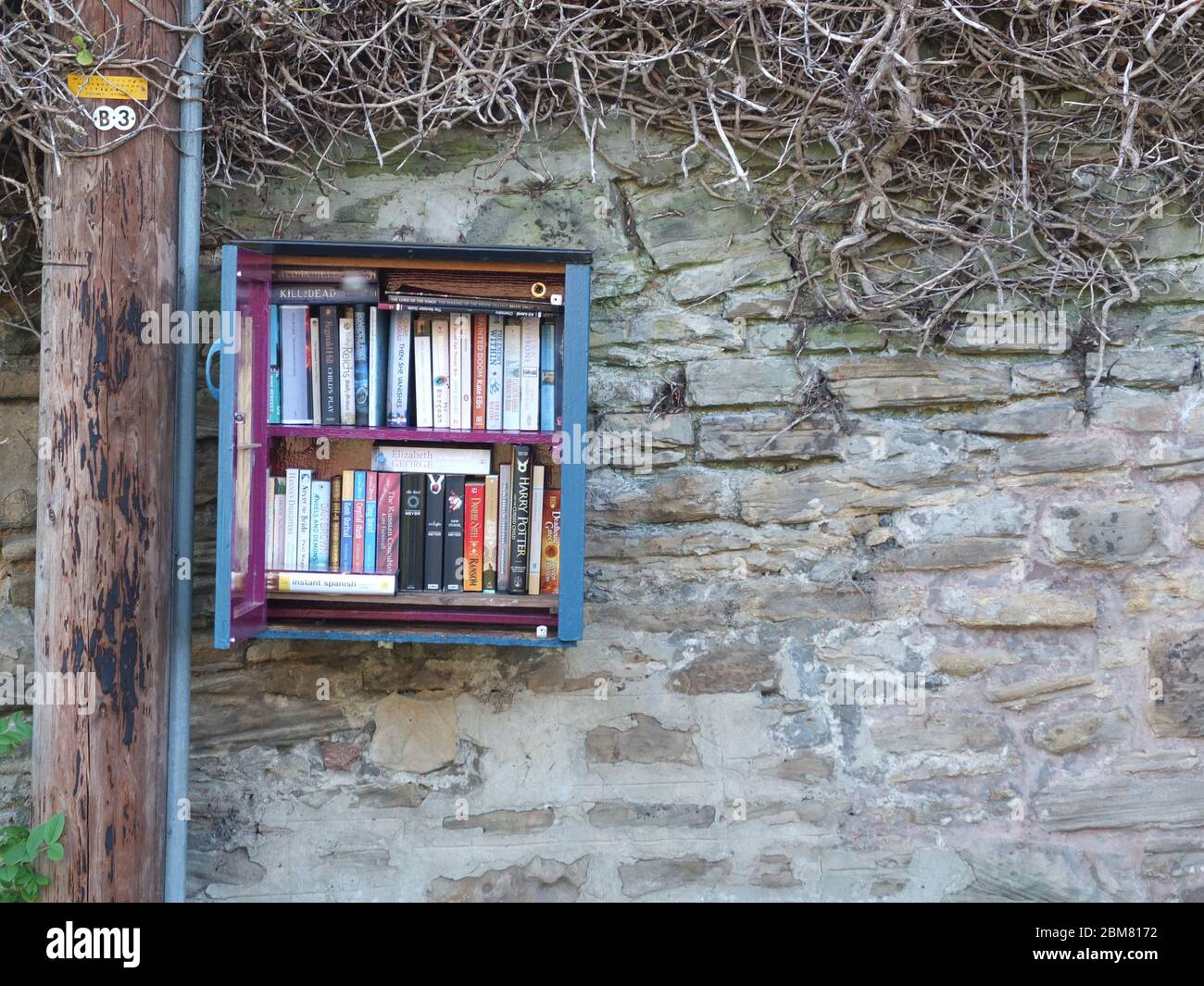 A box containing a free book exchange set up on the wall of a house in Sheffield during Coronavirus Lockdown for people to swap books for free Stock Photo