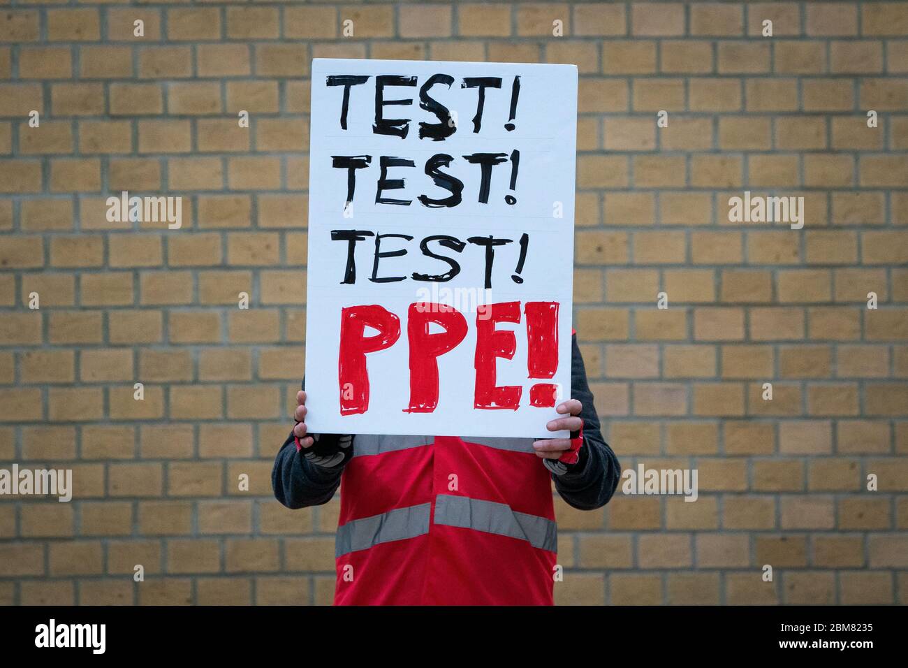A member of the public protests about PPE and testing outside Whittington Health in London join in the applause to salute local heroes during Thursday's nationwide Clap for Carers initiative to recognise and support NHS workers and carers fighting the coronavirus pandemic. Stock Photo
