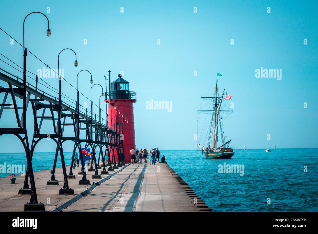 Tall ship sailing past a light house on a summer day Stock Photo