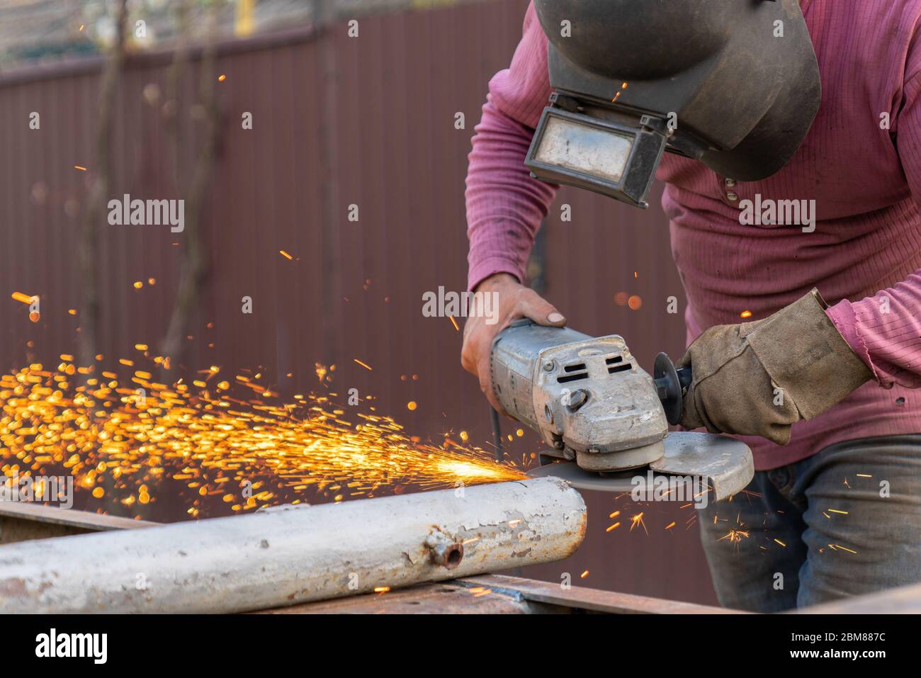 Craftsman sawing metal with disk grinder in the backyard Stock Photo