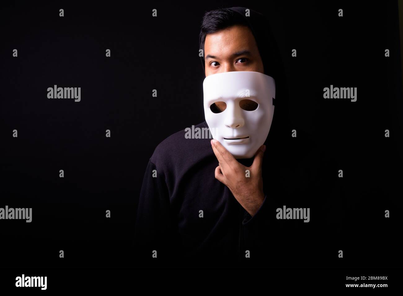 Portrait of young Asian man with hoodie wearing mask Stock Photo